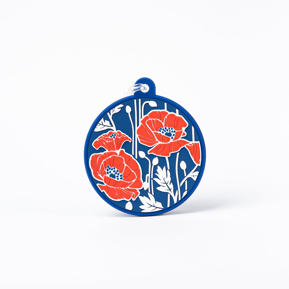 A royal blue circular luggage tag featured a red and white poppy design