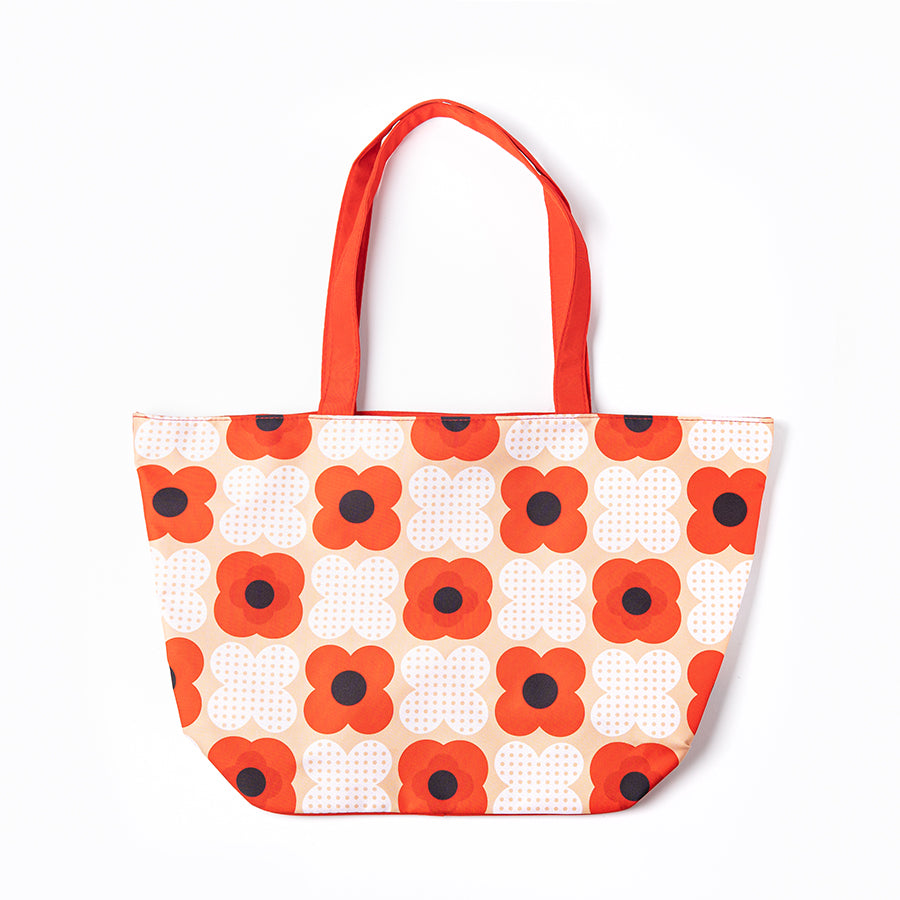 A beach bag featuring a stylised poppy design in red white and cream 